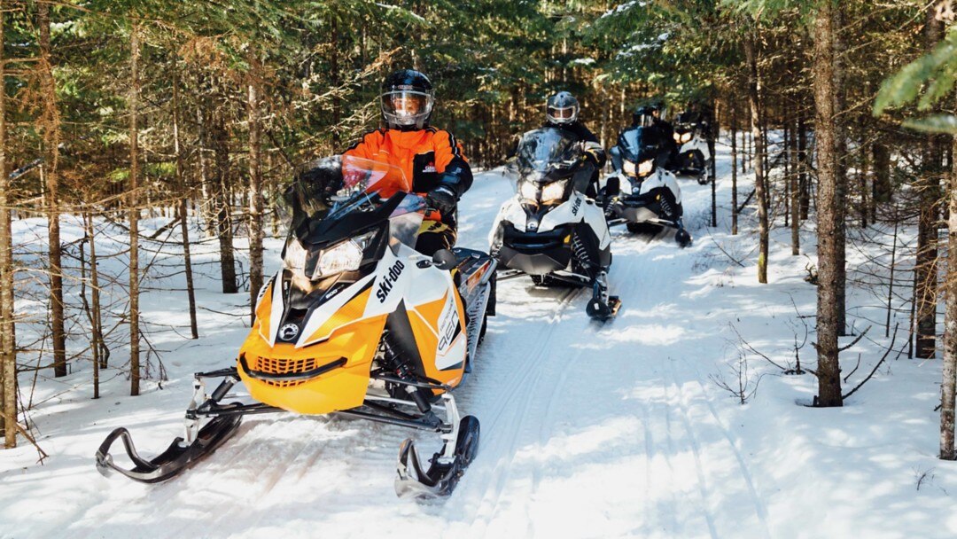 Un groupe de personnes roulant en Ski-Doo dans un sentier.
