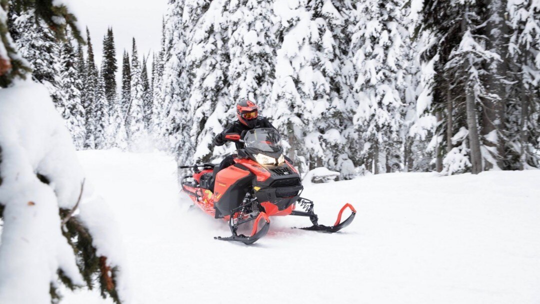 A snowmobiler driving a Ski-Doo on a trail