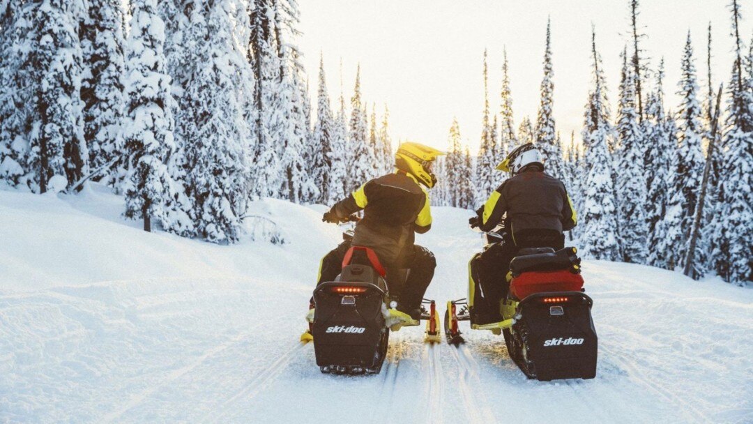 Deux motoneigistes discutant sur leur Ski-Doo dans un sentier.