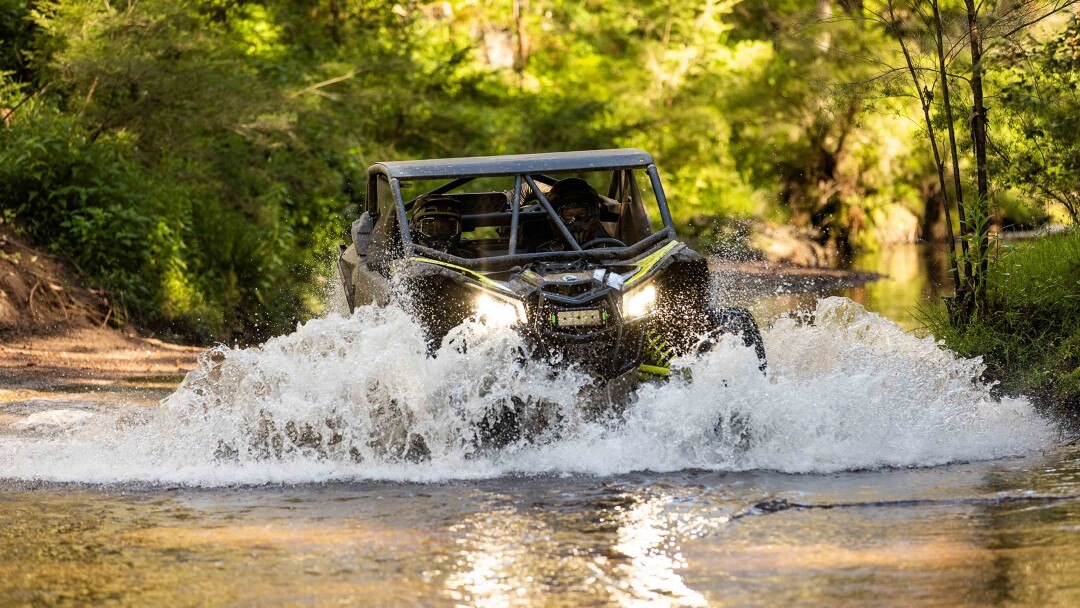 A rider driving through water with a SxS