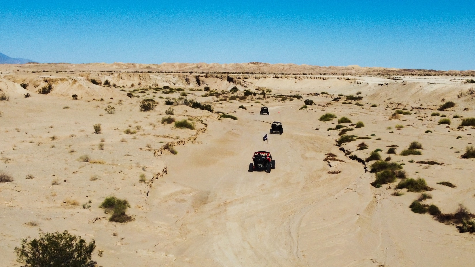 Four Can-Am SxS vehicles riding in the desert