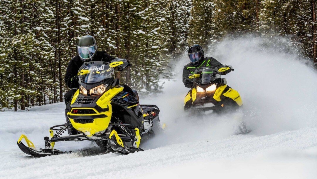 two yellow Ski-Doo in the forest 