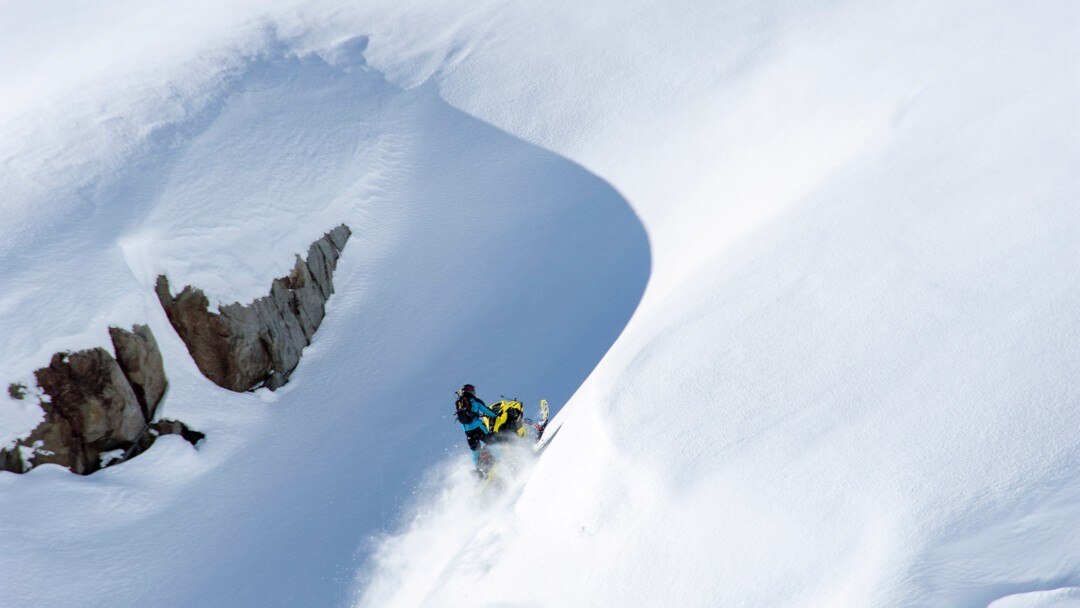 Une personne escaladant une montagne avec sa motoneige
