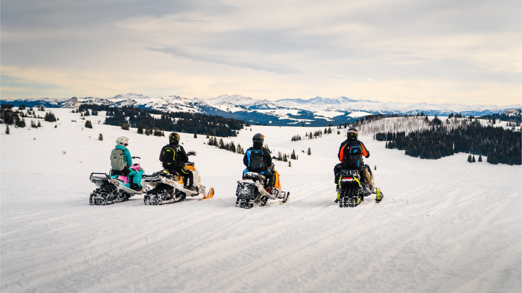  Four Ski-Doo snowmobile riders overlooking the Wyoming landscape