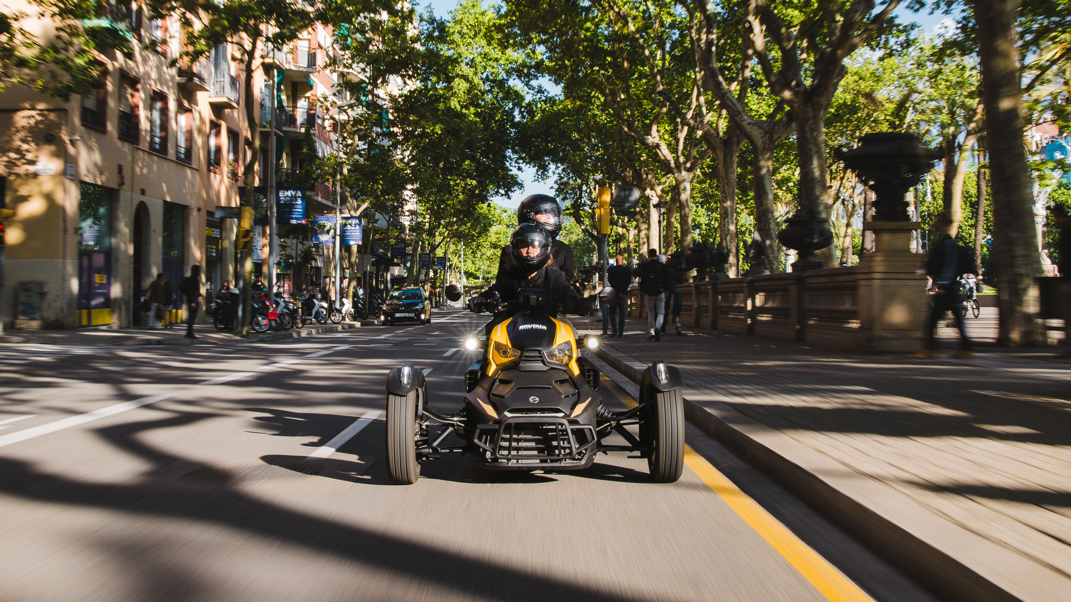 Two people riding a 3-wheel vehicle in a city