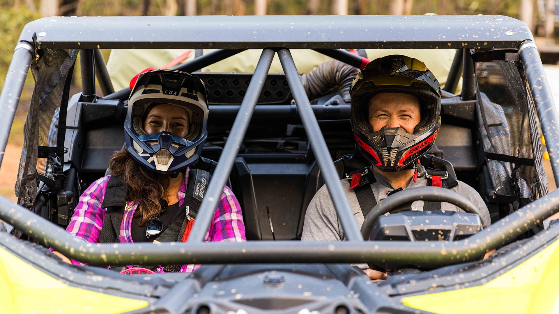 Two riders smiling in a Can-Am SxS