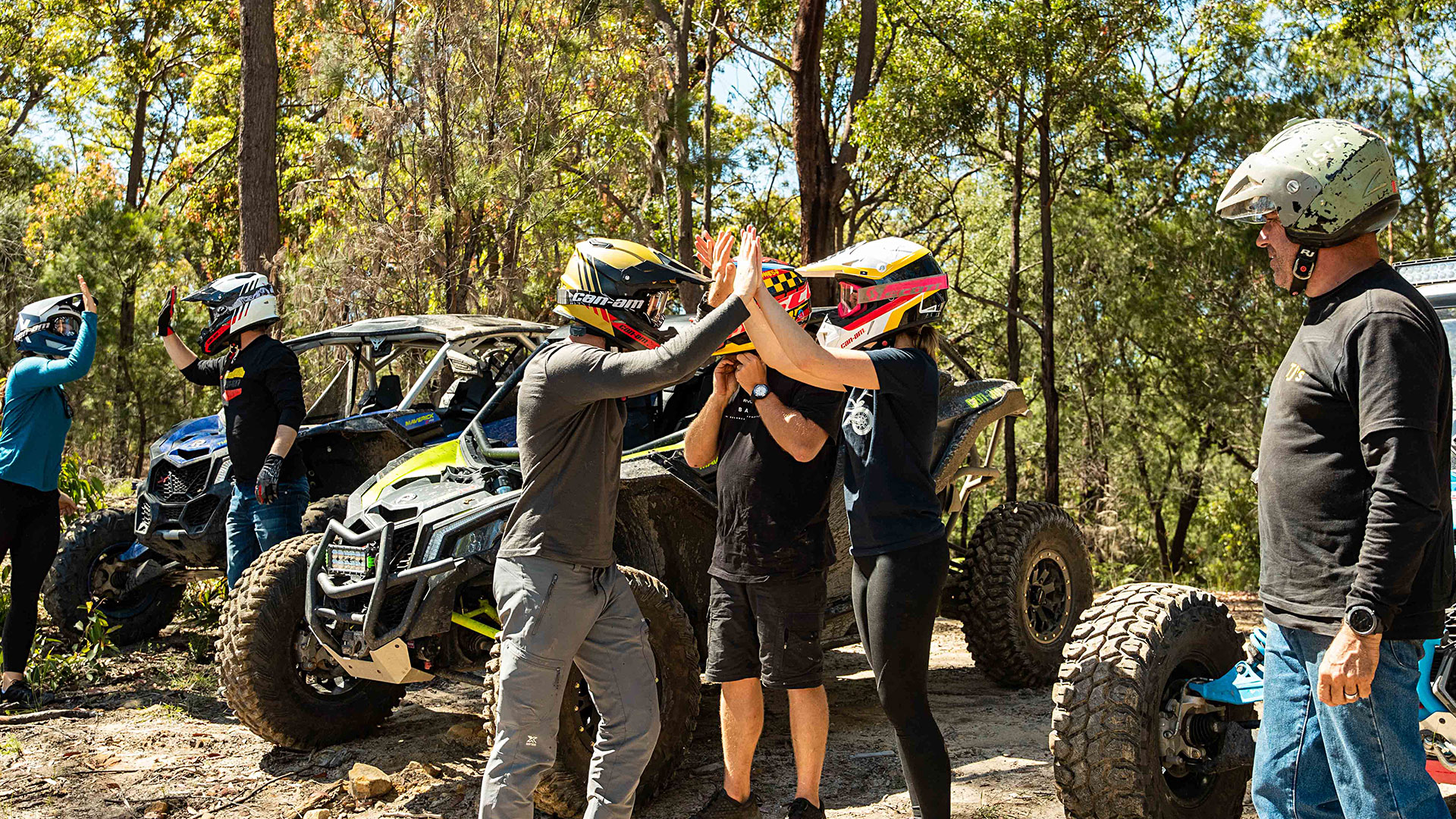Riders high-fiving near Can-Am vehicles