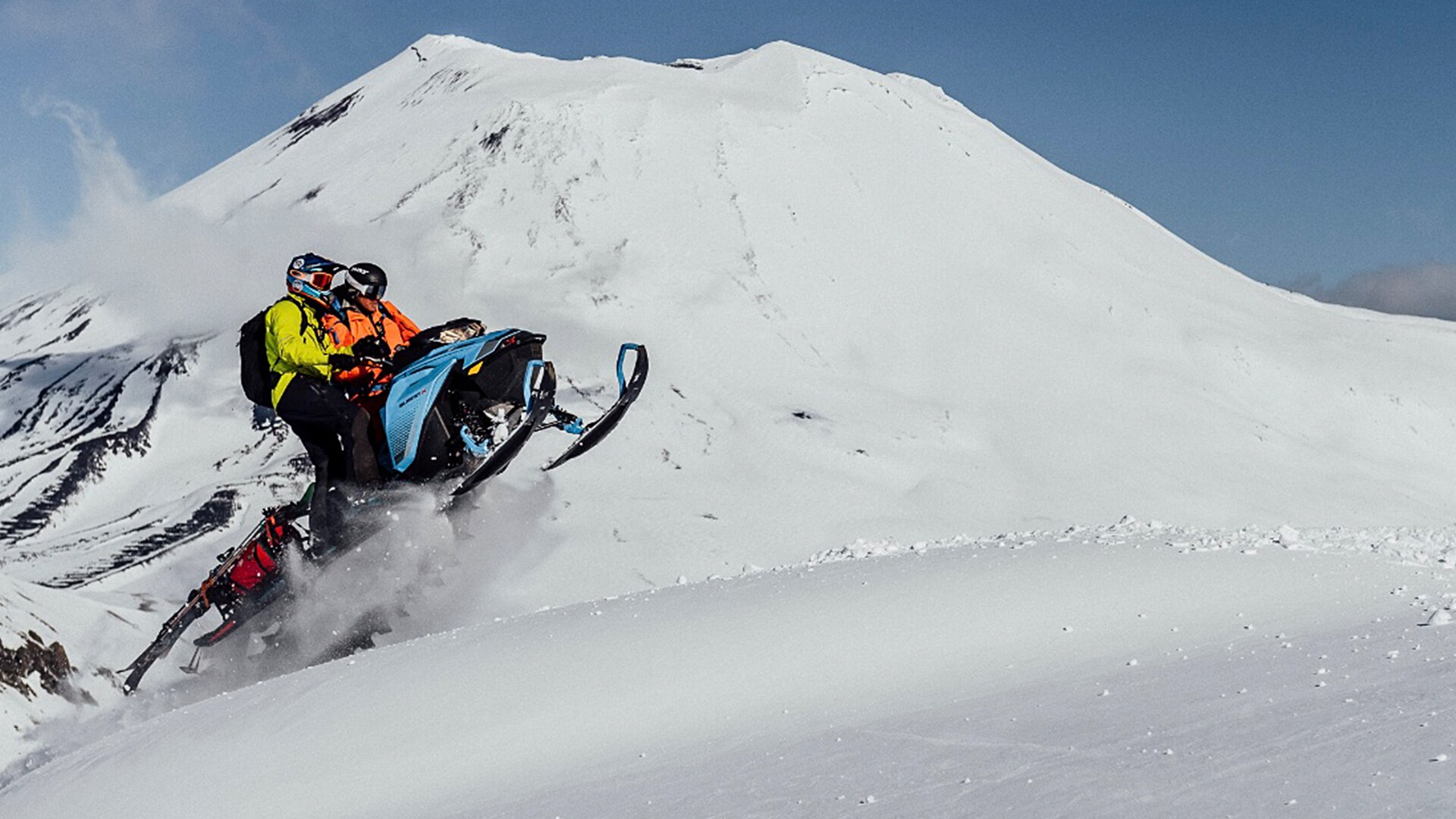 Two people making a jump on a snowmobile