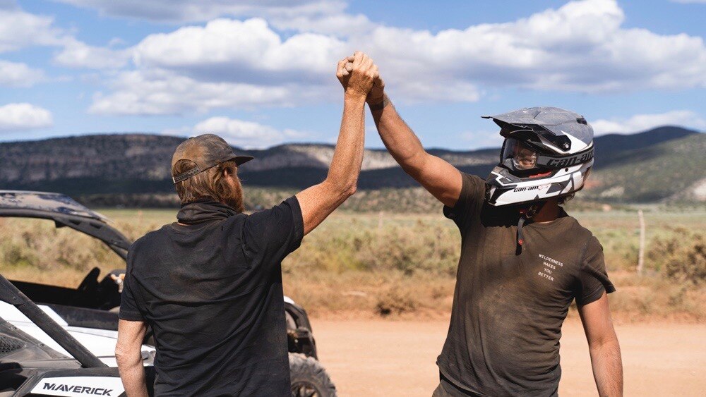 Men high five with Can-am and helmet