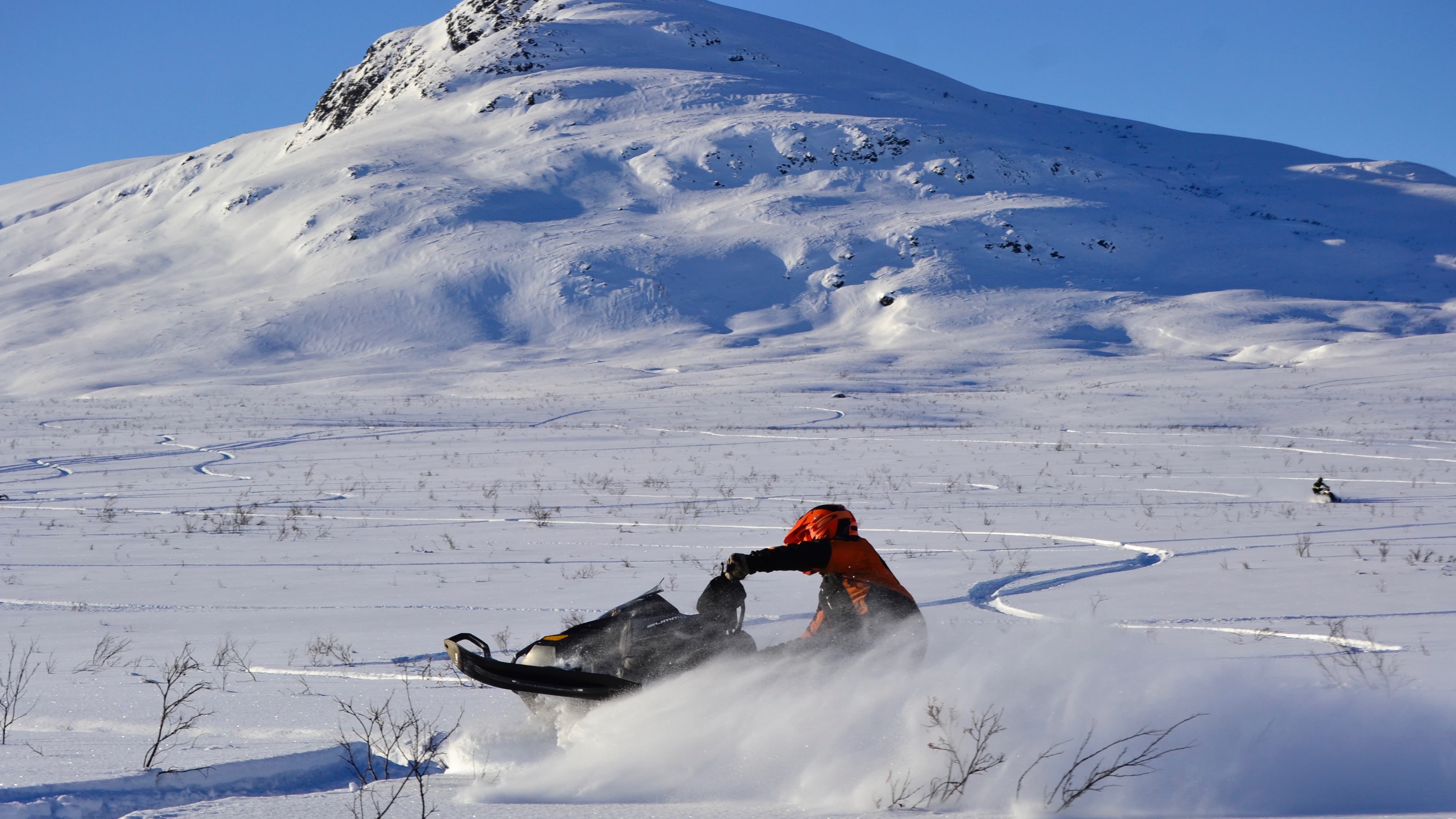A man riding a snowmobile in front of the mountain