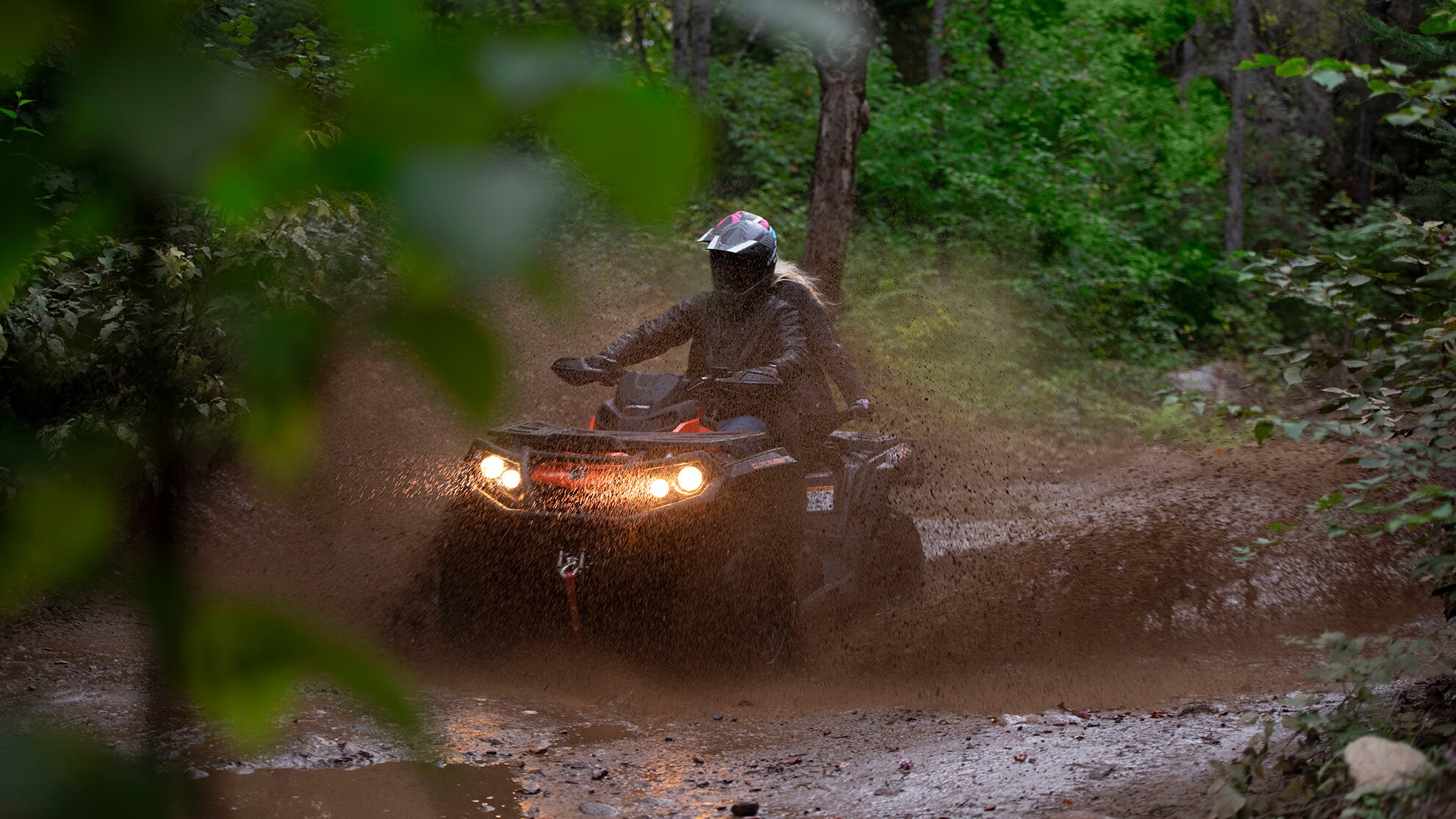 A couple on an ATV riding in the mud 