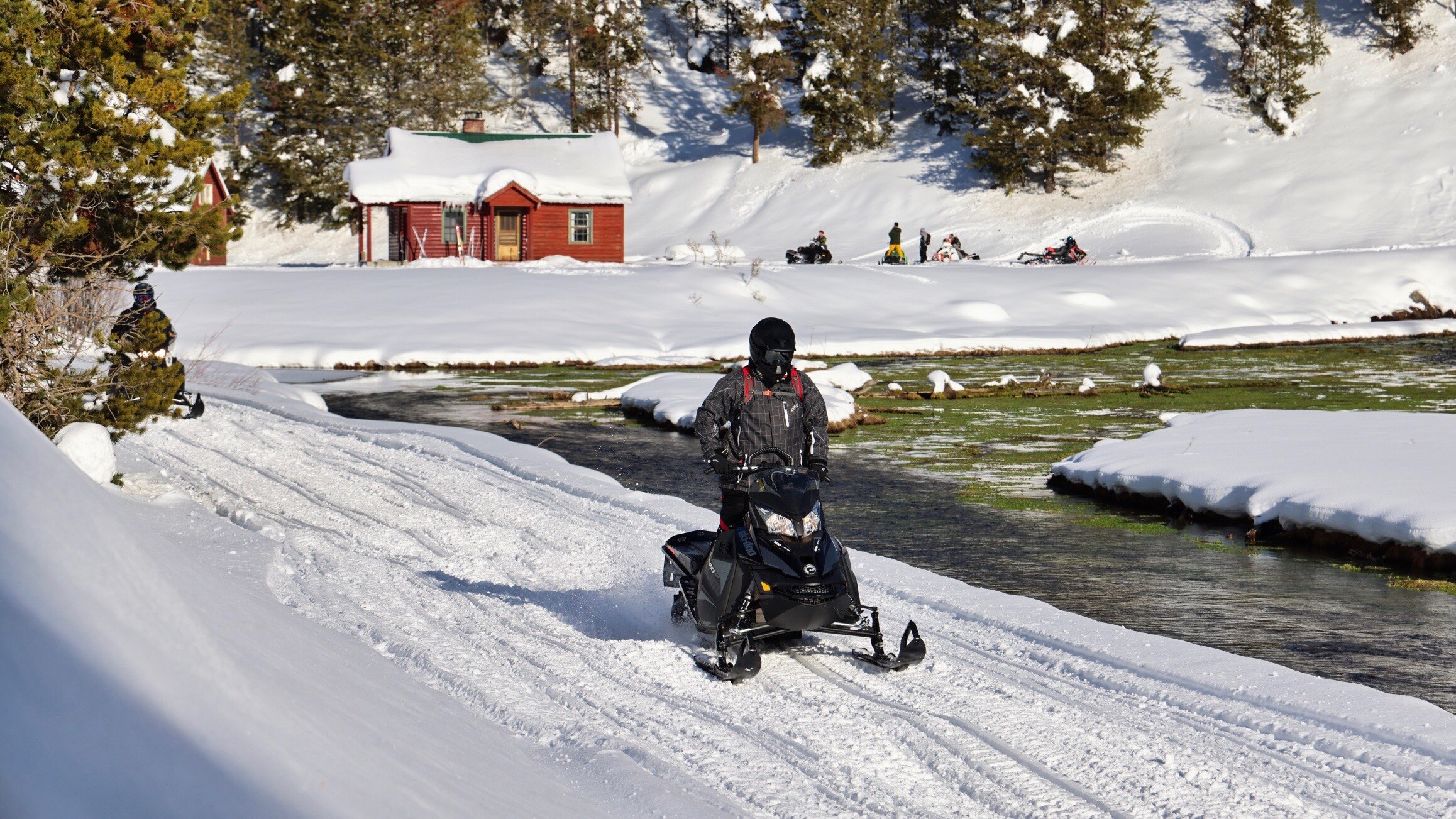A man riding a snowmobile along a river