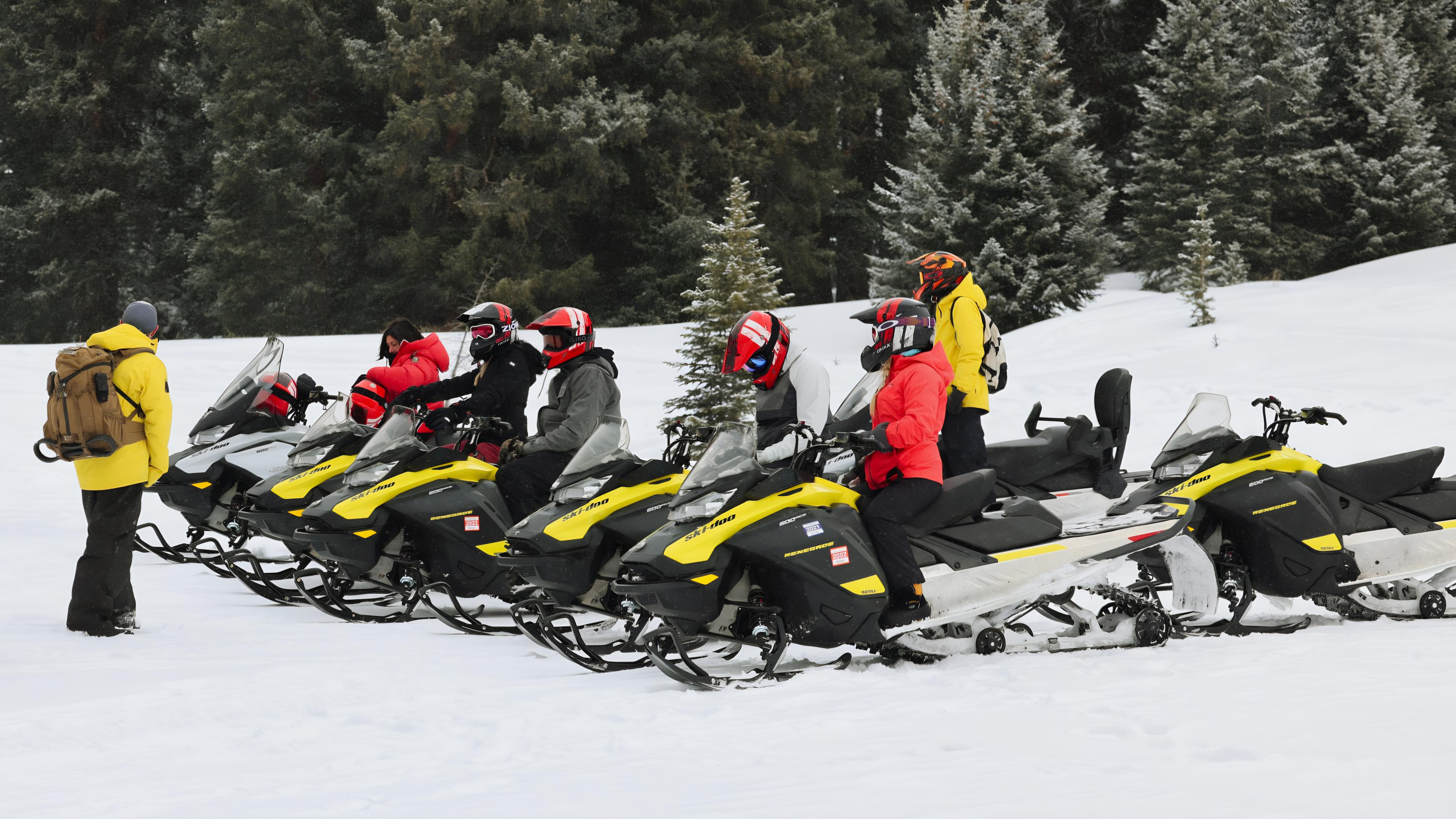 A snowmobile guide talking to riders on snowmobiles