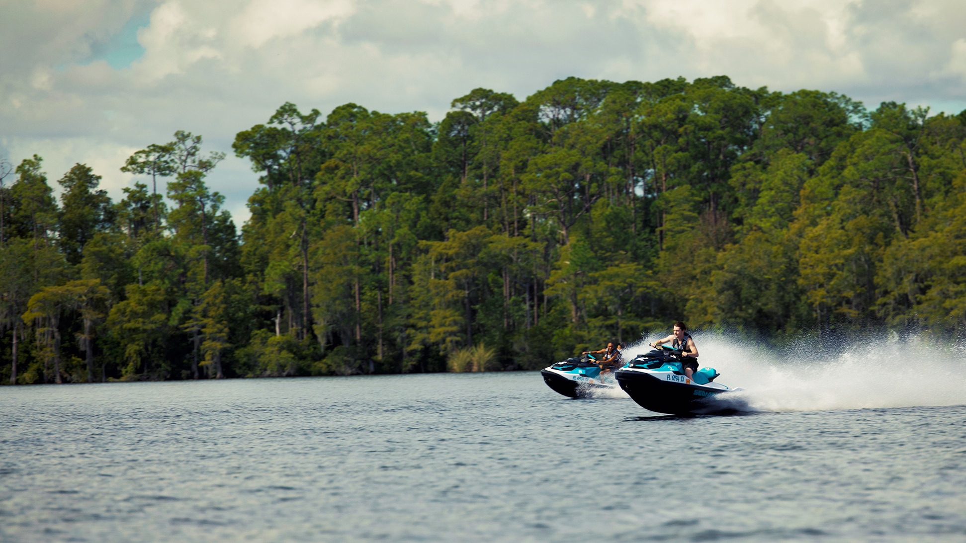 Two persons each riding a personal watercraft on the water