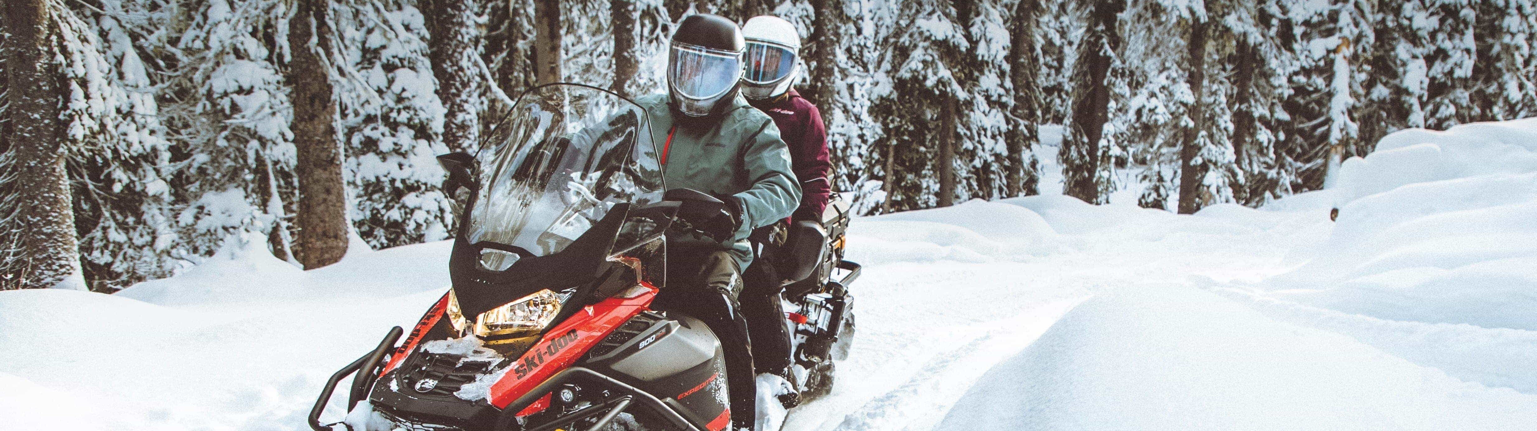 Two people riding a Ski-Doo on a trail