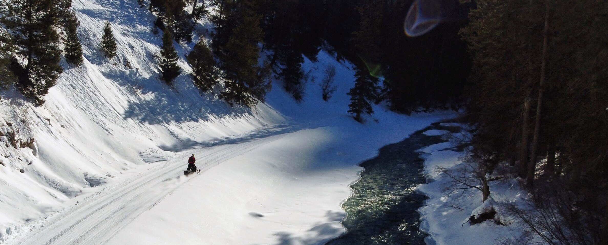 Snowmobiler riding next to a river