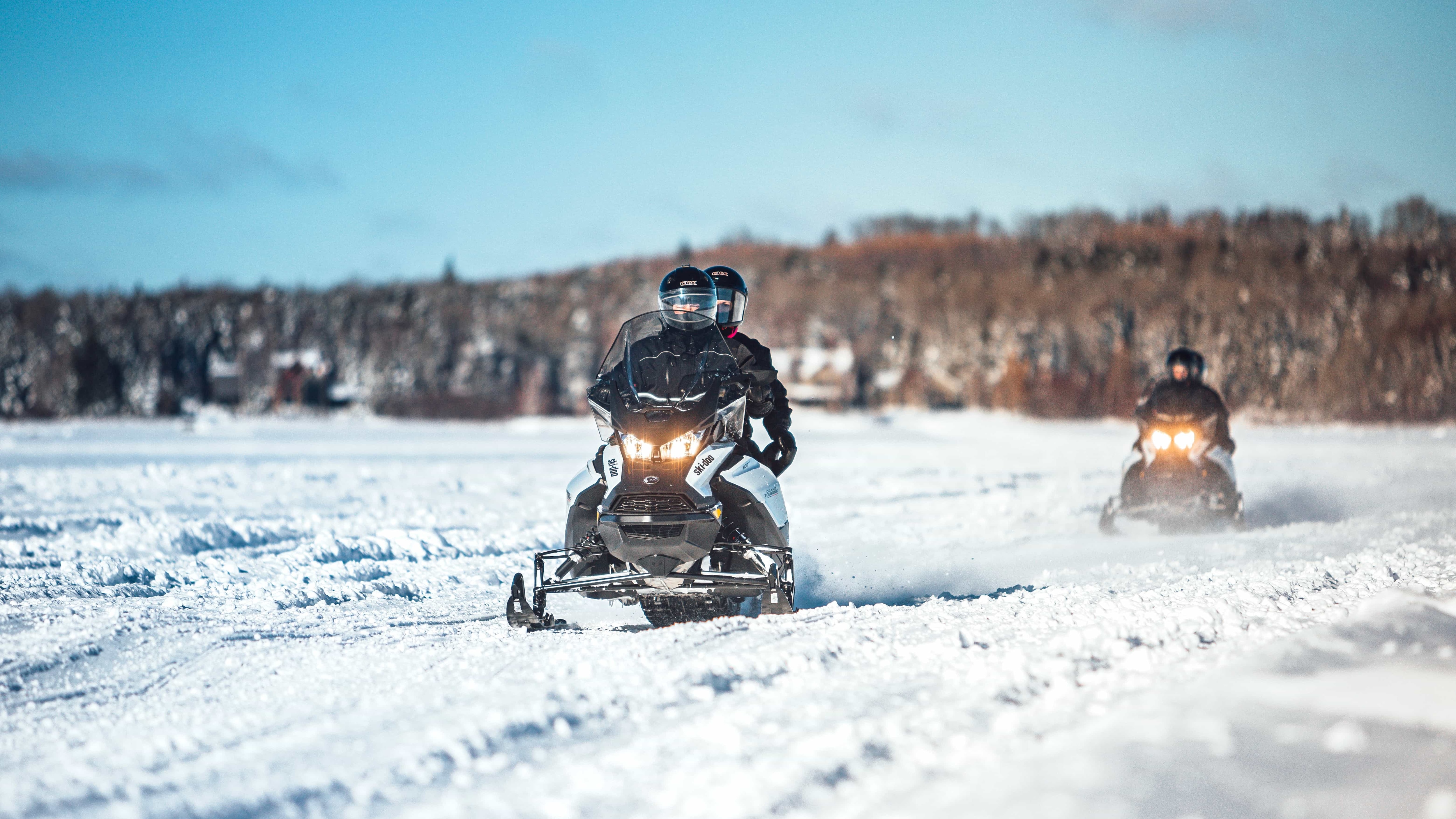 Two snowmobiles riding on a frozen lake