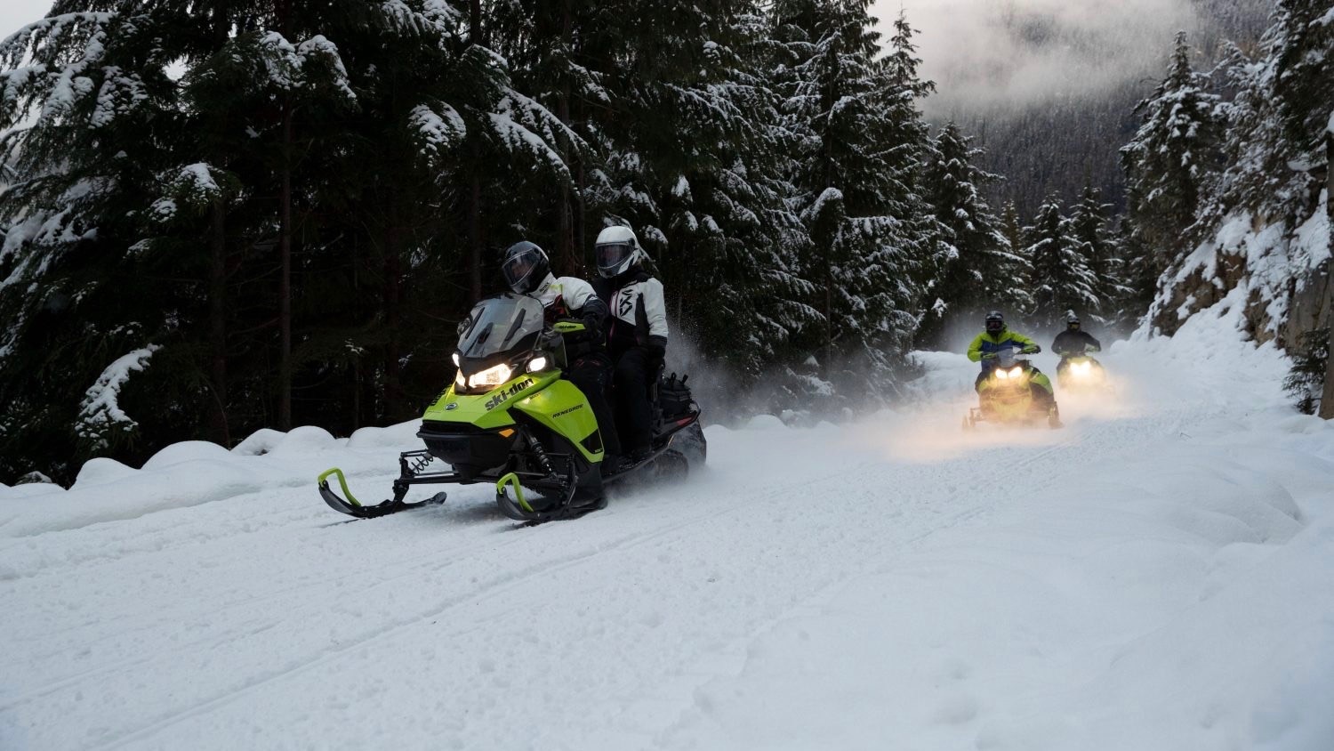 A group of snowmobilers riding in a trail