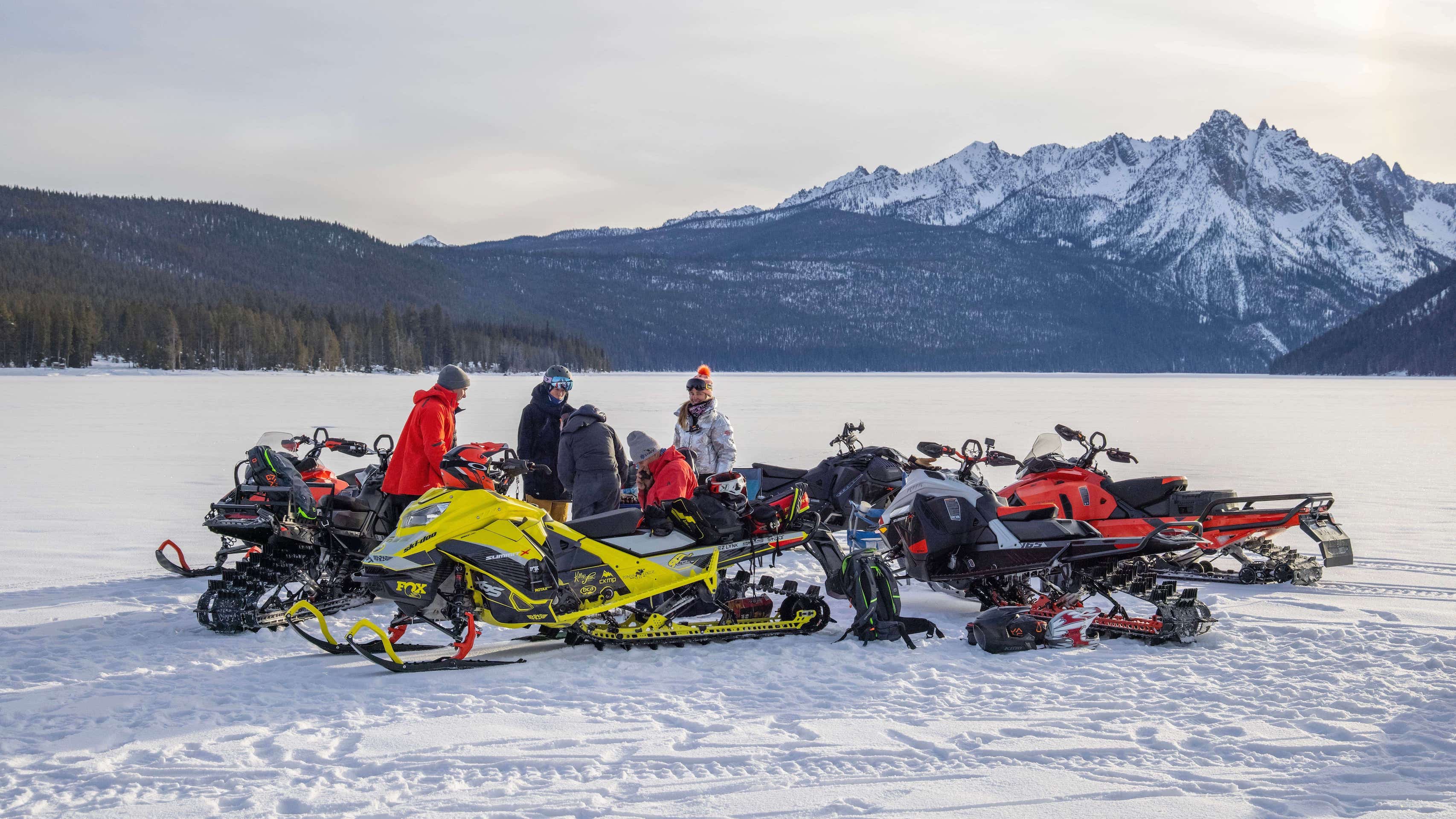 Crew of snowmobilers in front of mountains