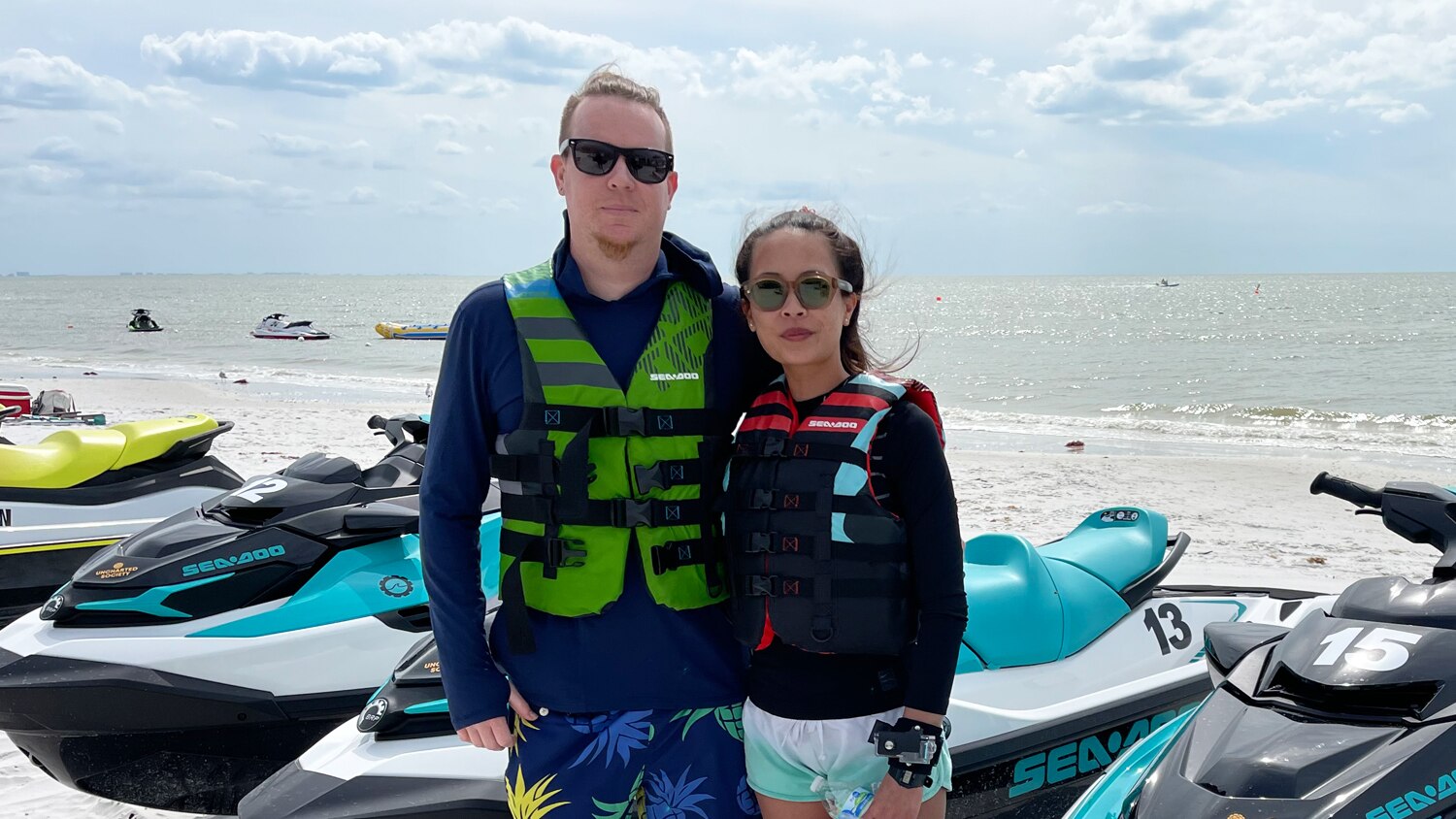 Un couple sur la plage devant des motomarines Sea-Doo
