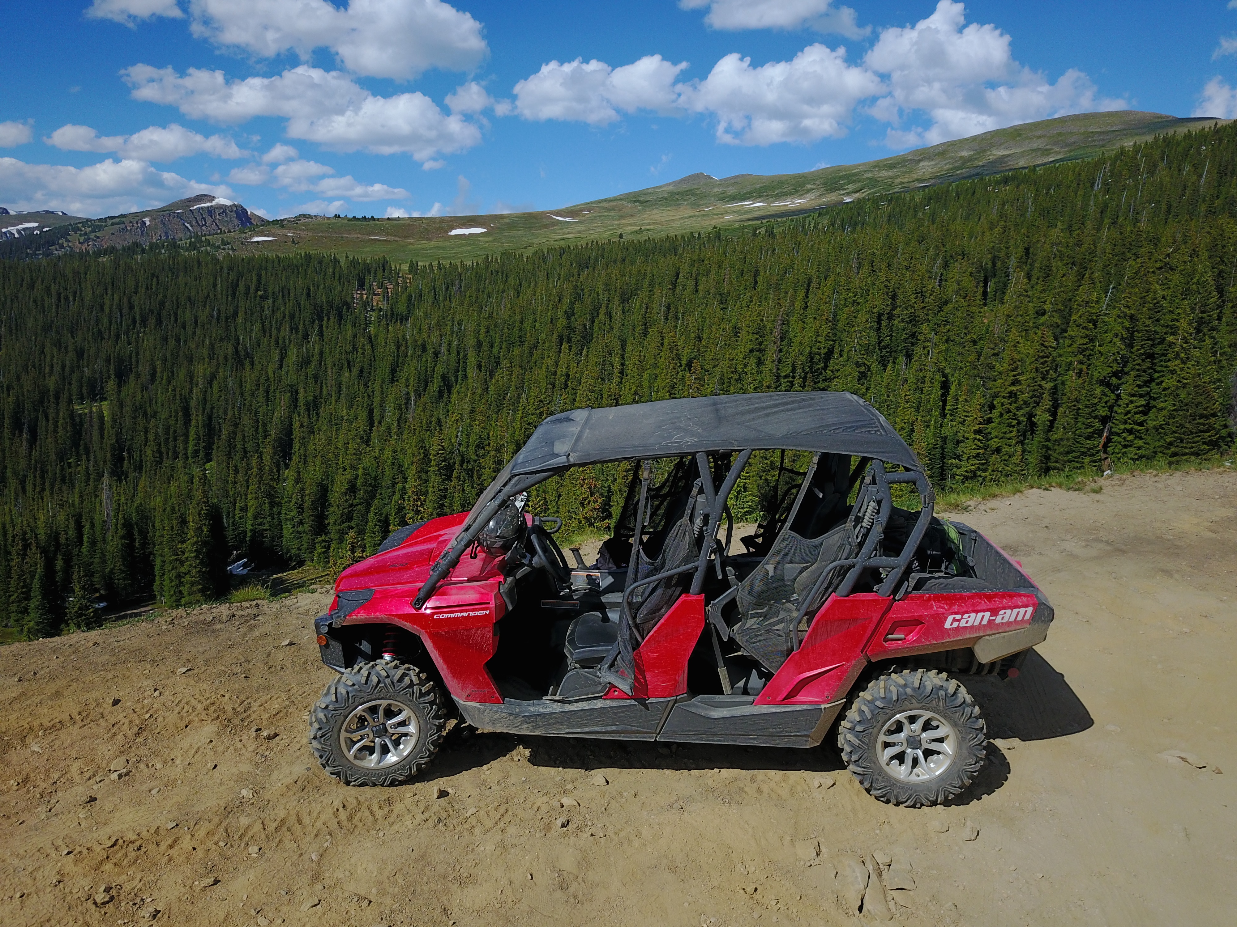 A red Can-Am unit parked with mountains and trees in the background