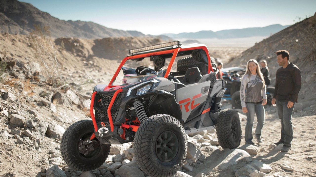 A couple in the mountain standing next to their Can-Am SSV