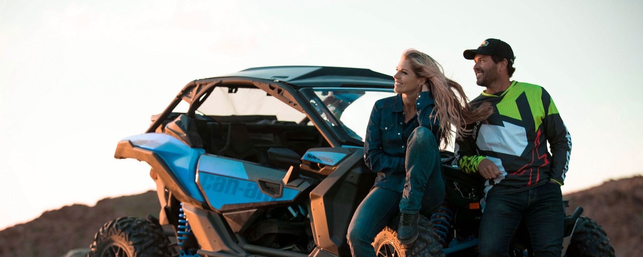 A couple relaxing next to a Can-Am Off-Road vehicle