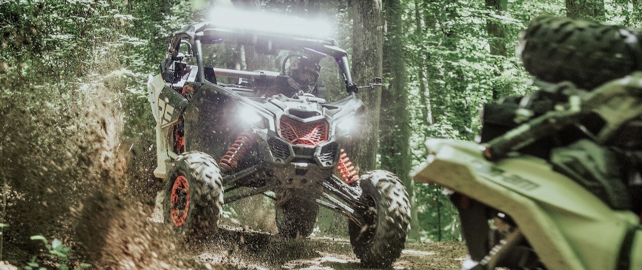 Two Can-Am Off-Road vehicles riding in the woods