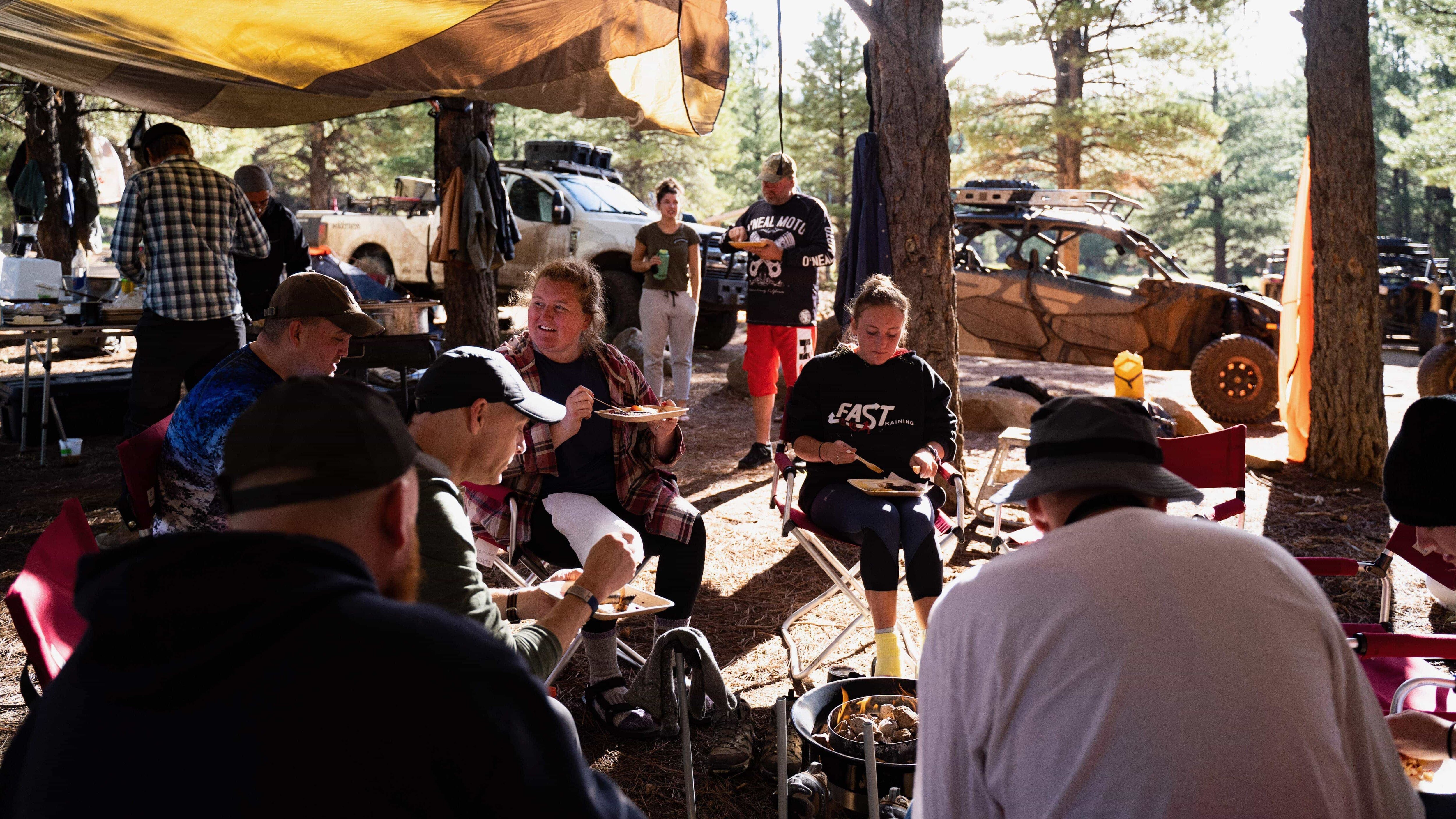 A group of people eating sitting on a camp site