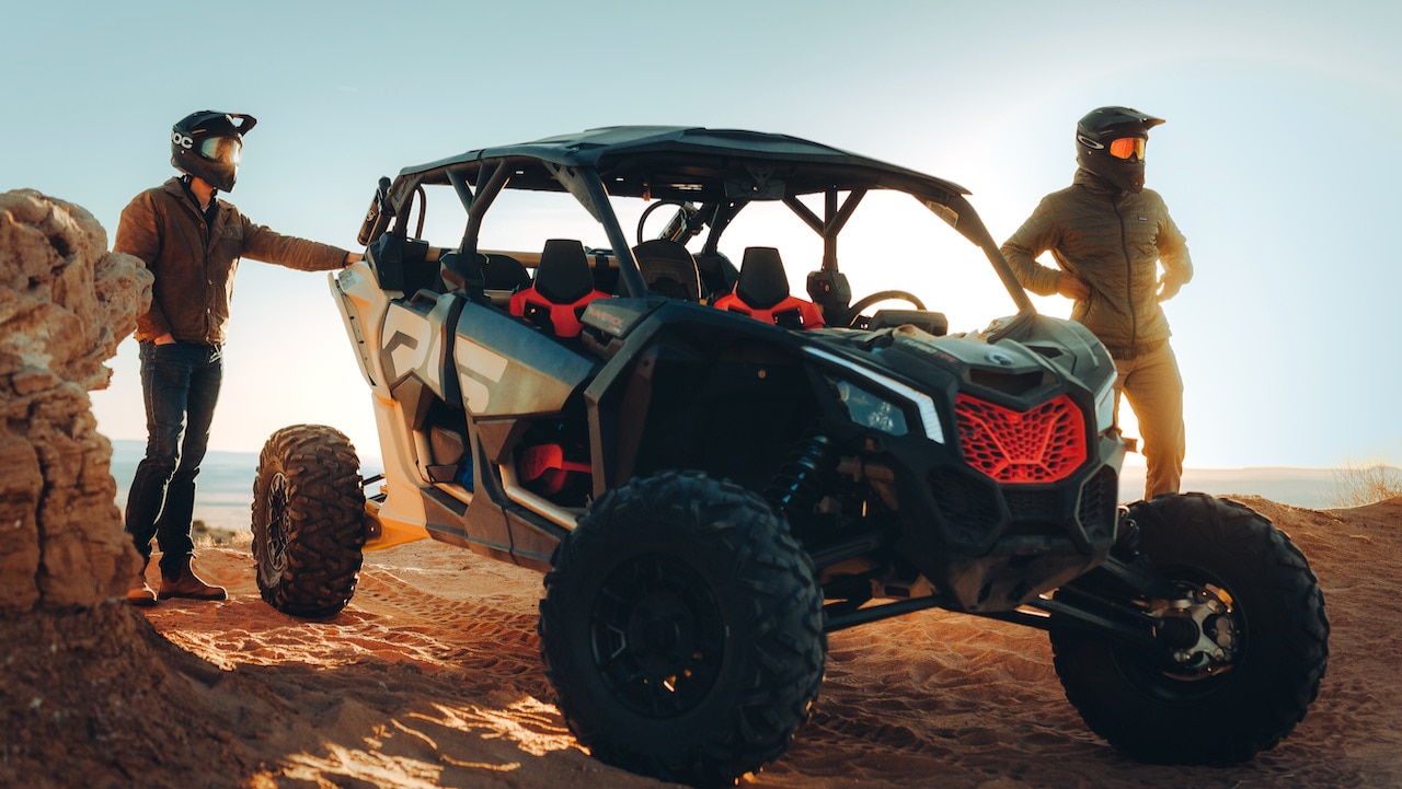 Two men admiring the desert view next to a parked Can-Am side-by-side