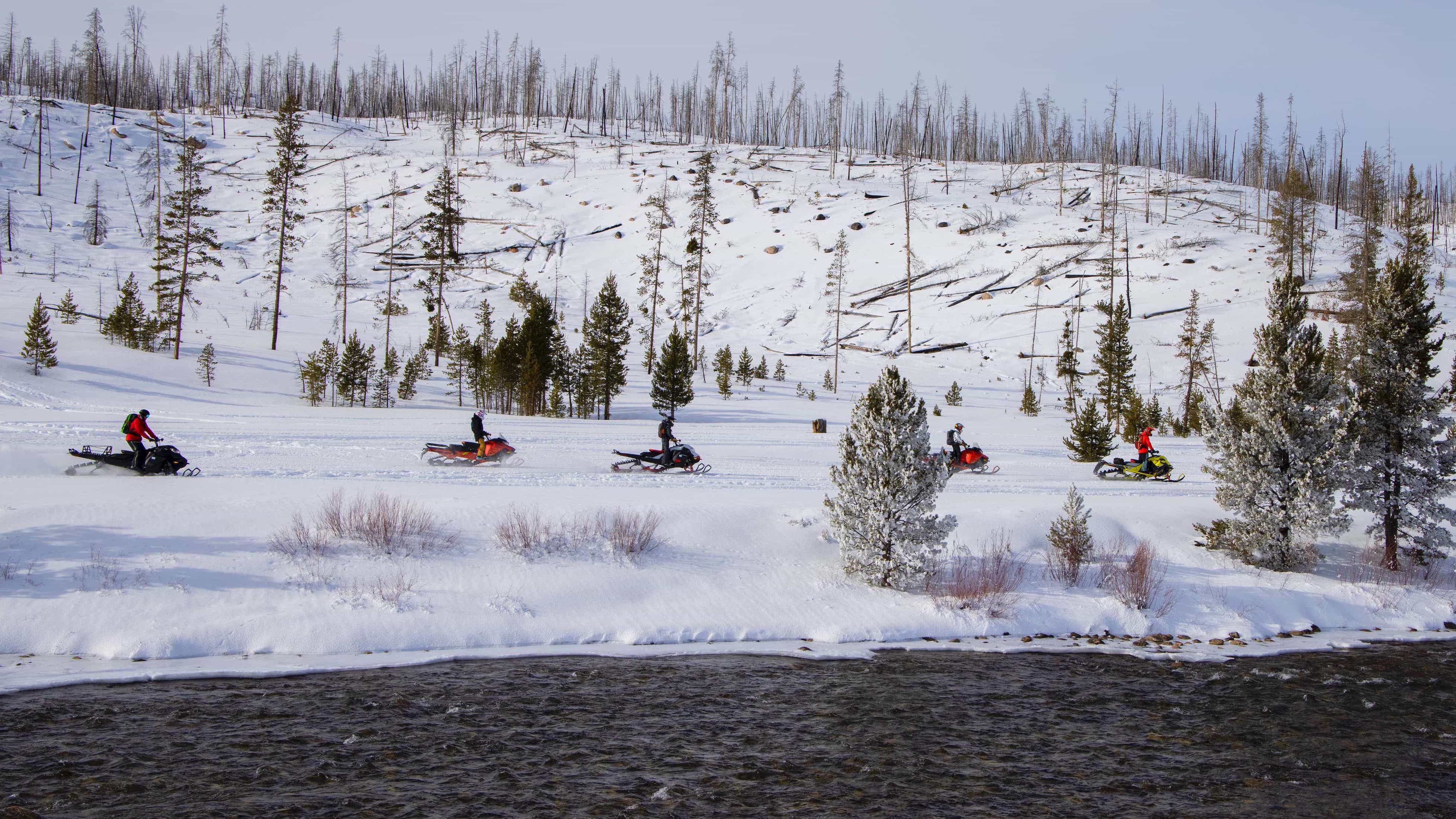 A group of snowmobilers riding a Ski-Doo along a river in Idaho 