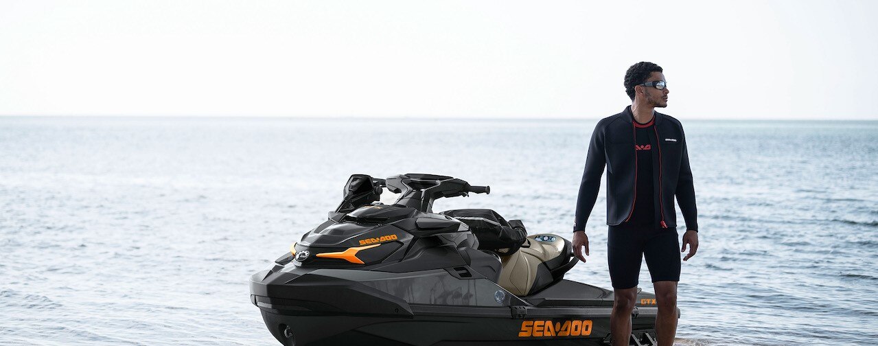 Man walking next to a Sea-Doo PWC on a beach