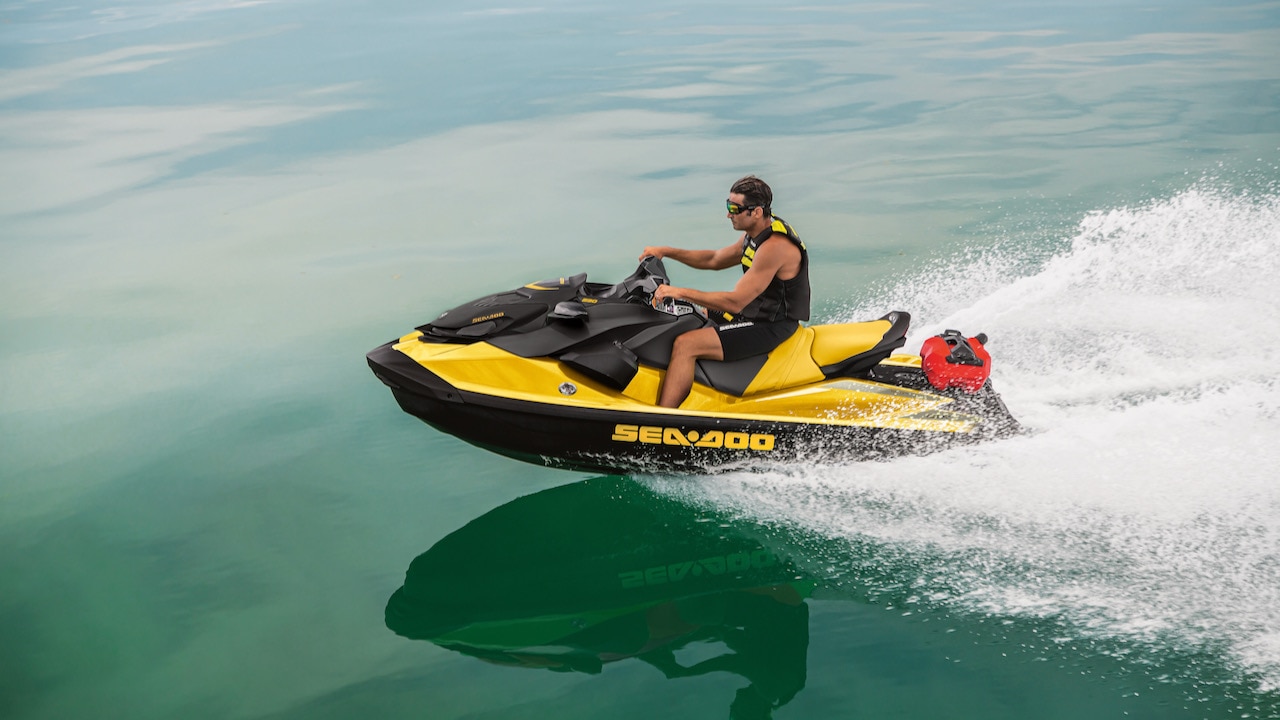 A man riding a Sea-Doo personal watercraft on blue water