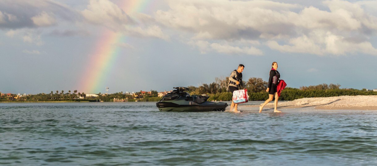 A couple going off a personal watercraft parked on a beach