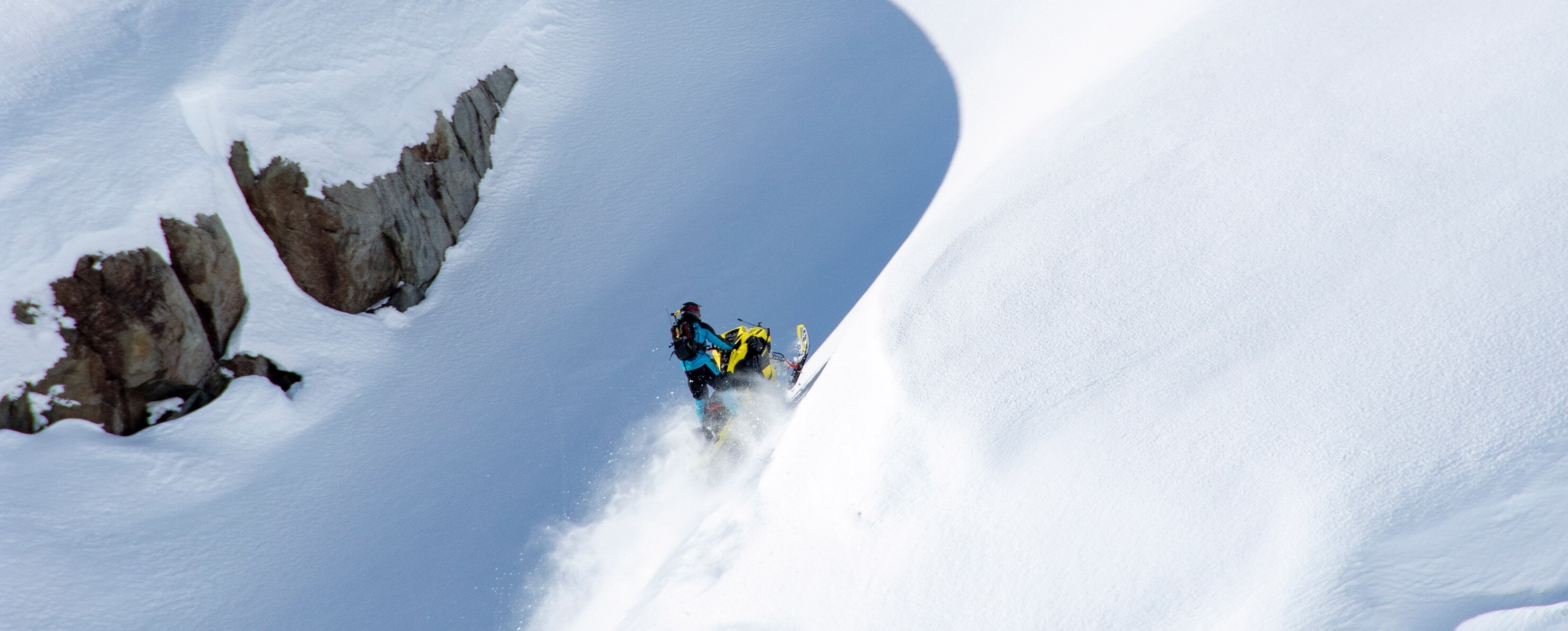 A person climbing a mountain with his snowmobile