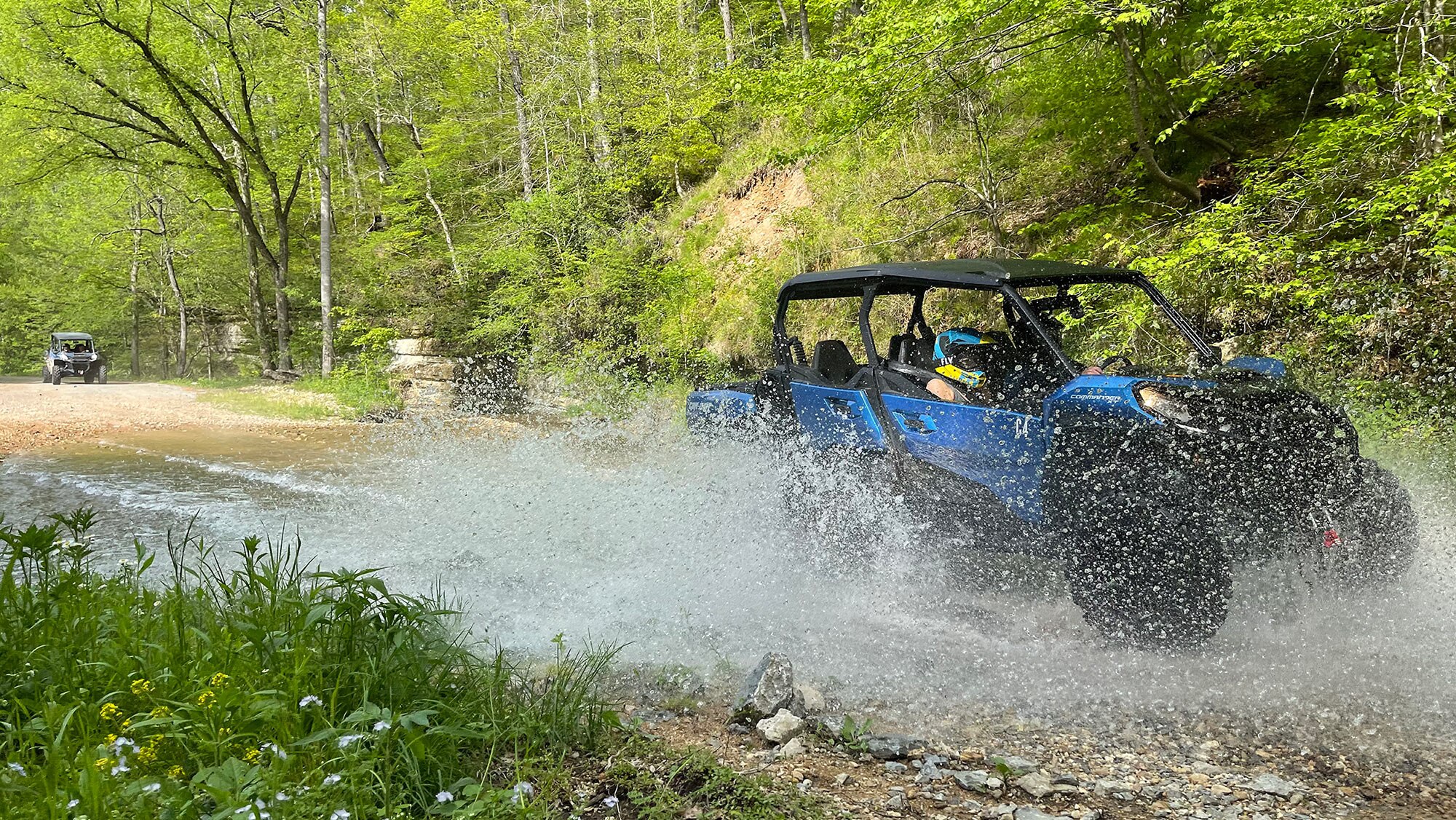 People riding in water with a side-by-side vehicle