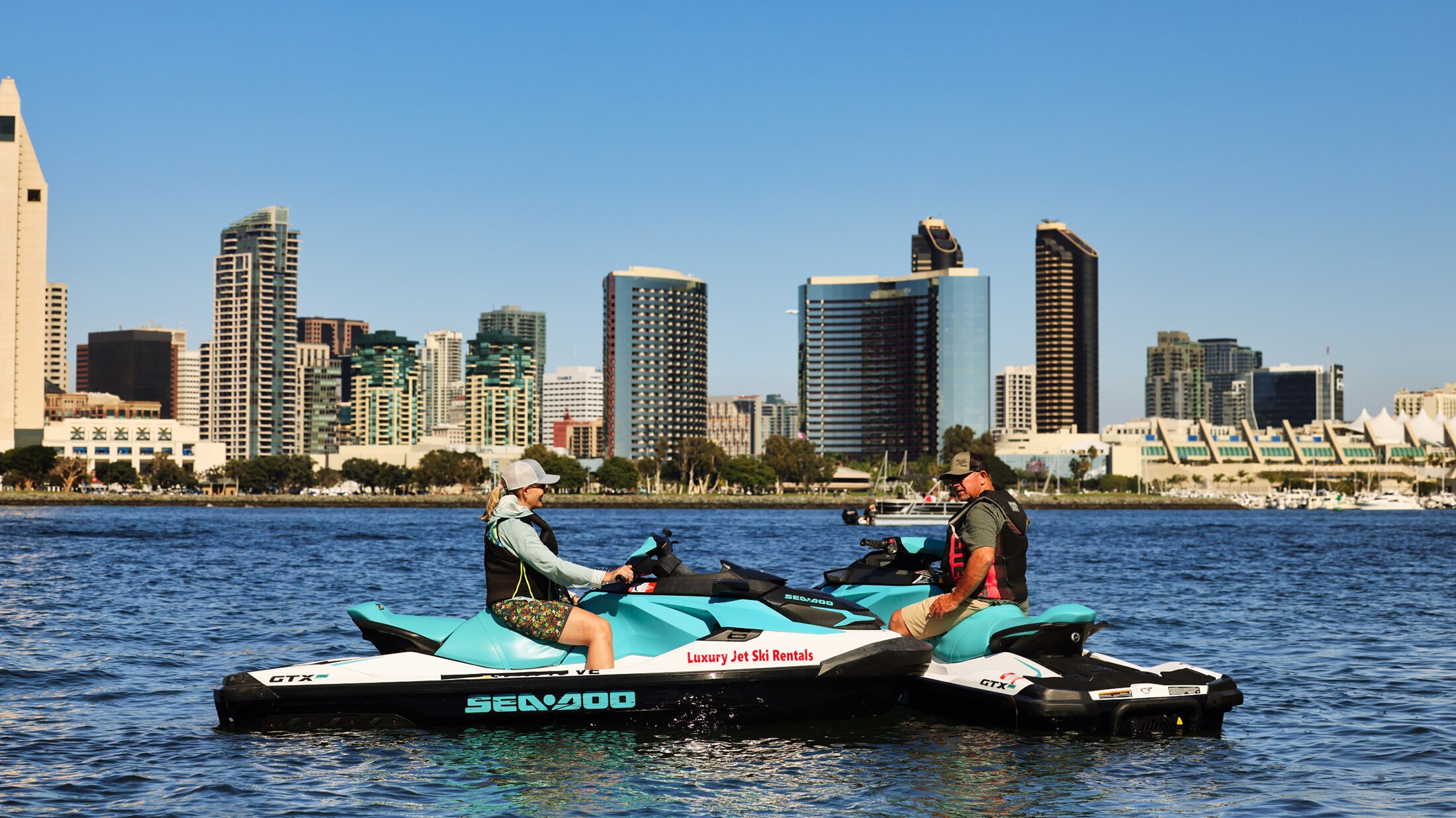 Two persons each on a Sea-Doo taking a break on the water
