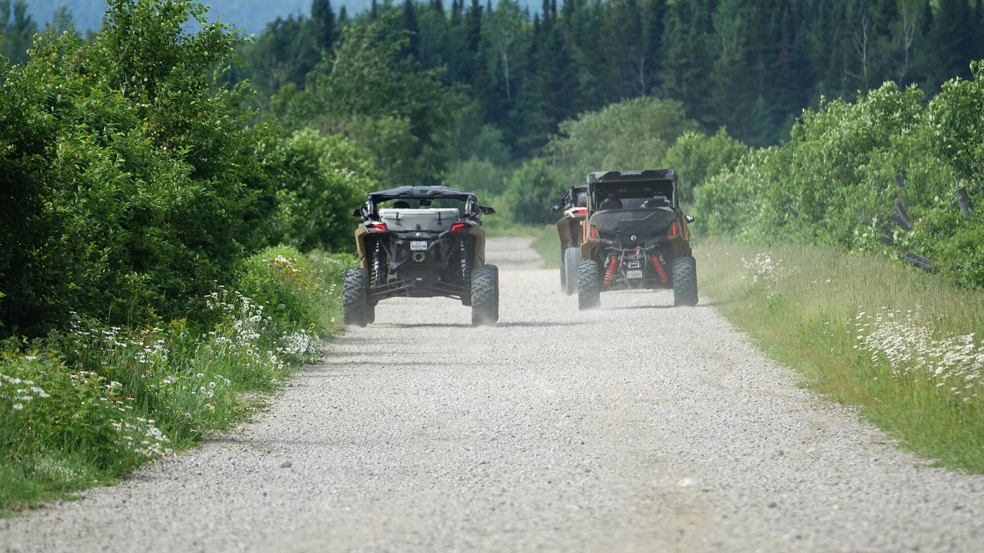 Two side by side vehicles riding on a gravel road