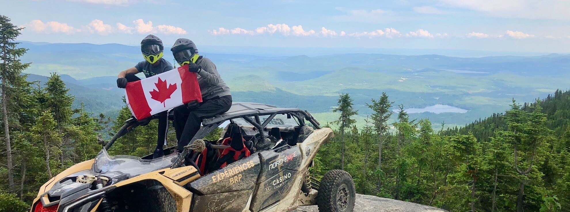 A unit parked on the top of a mountain with a Canadian flag and trees in the back 