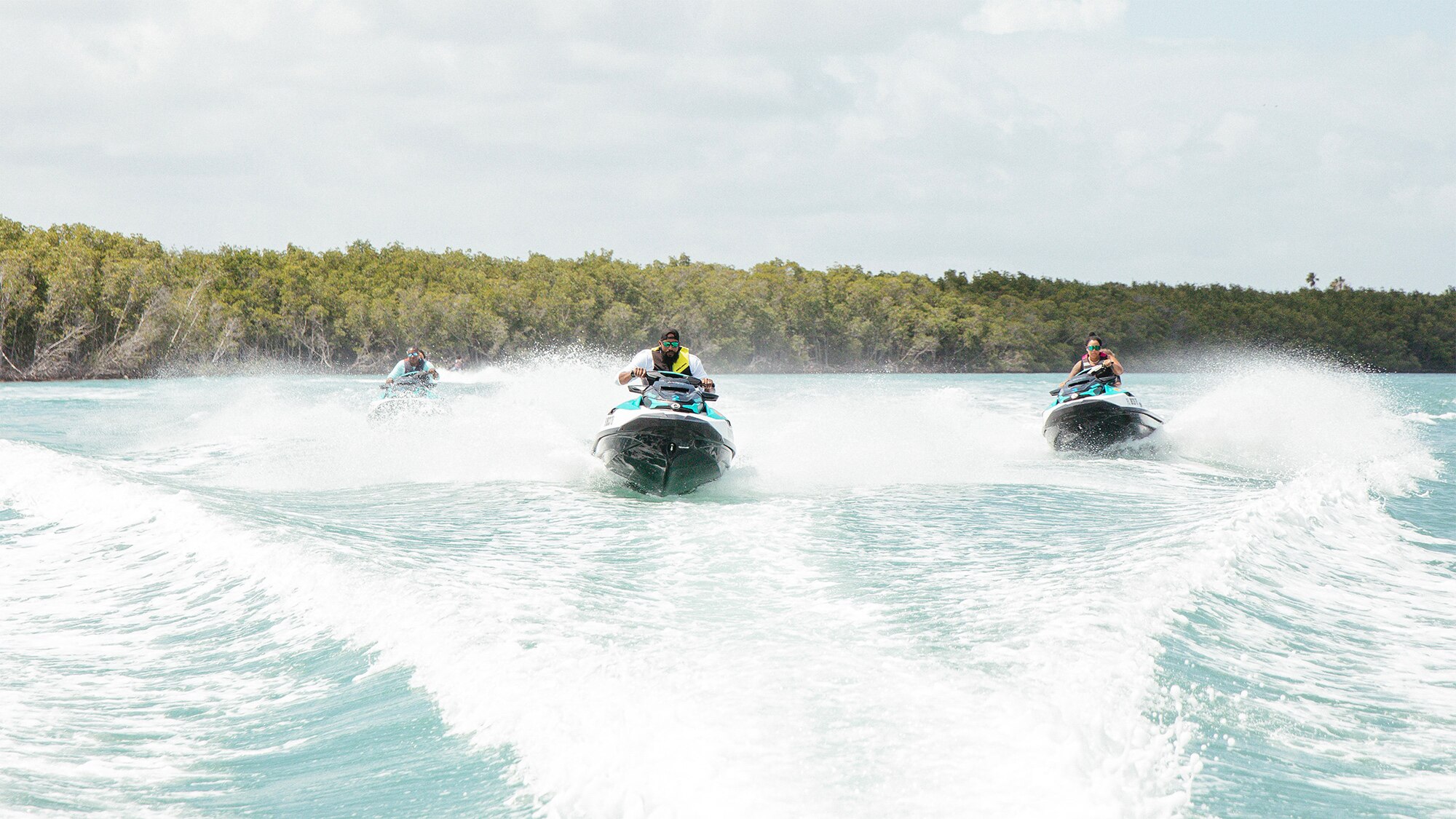 Three people each riding a personal watercraft on clear water