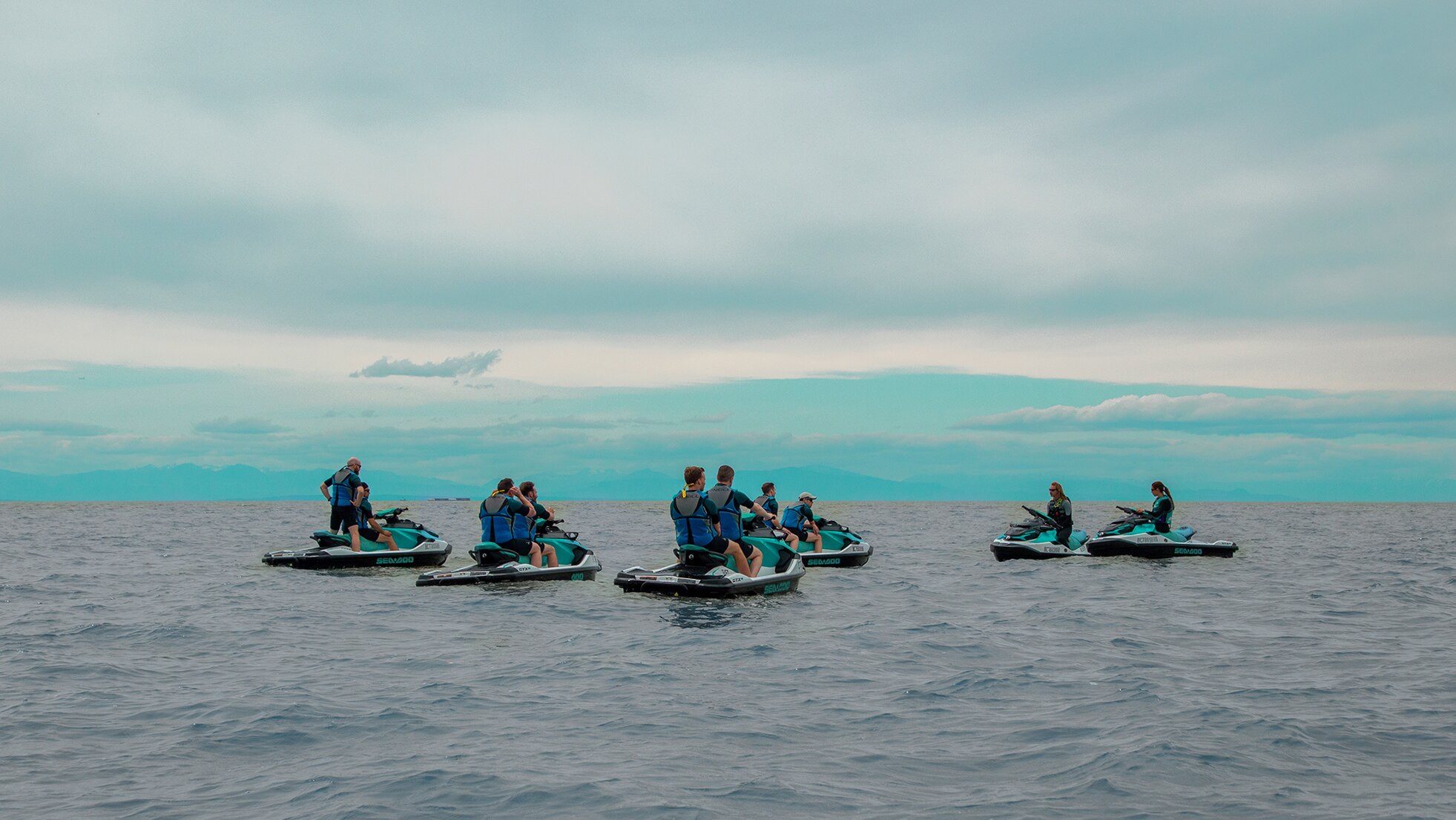A group of people on personal watercrafts in the middle of the water