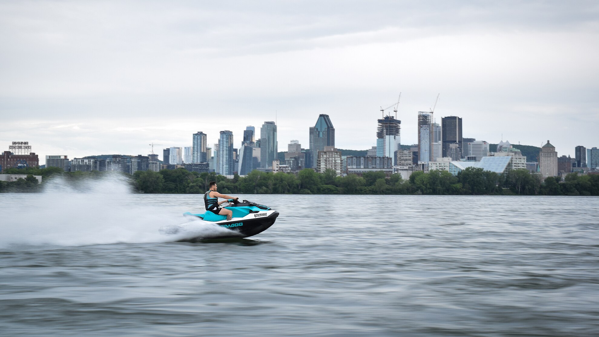 A man driving a Sea-Doo pwc with skyscrapers in the background