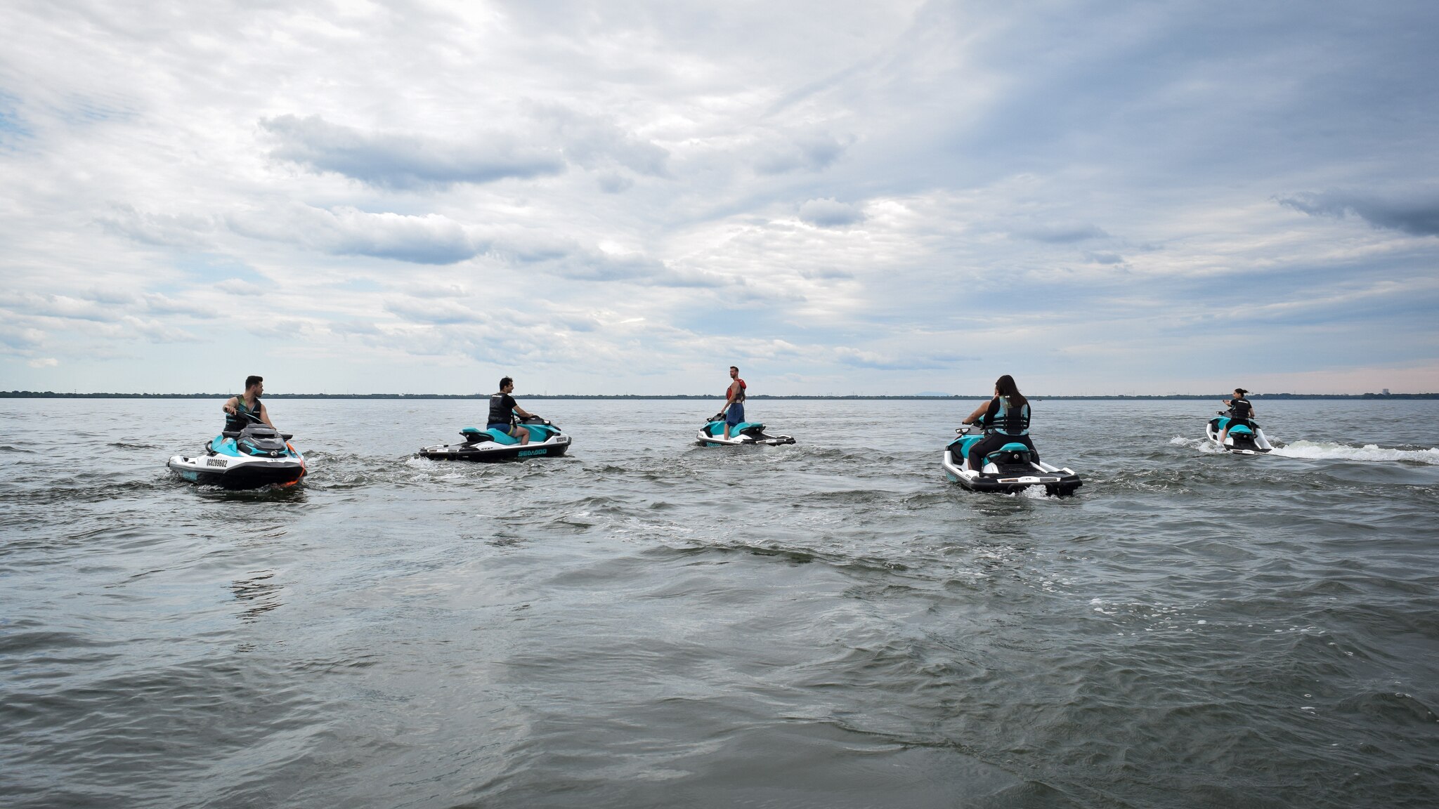 A group of people on Sea-Doo PWCs talking in the middle of the water