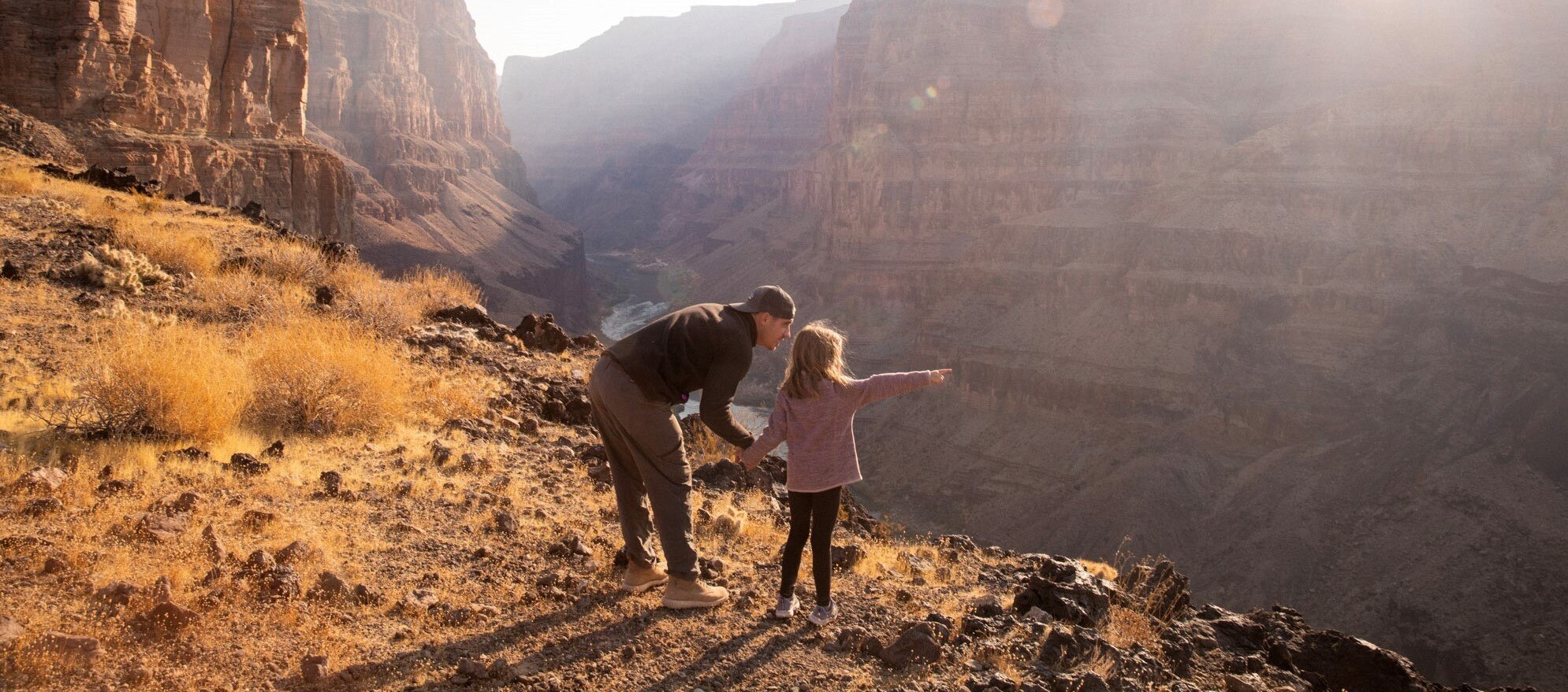 Man and young girl looking over and pointing at the view in the mountains