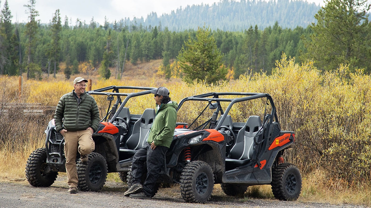 Can-Am riders discussing in front of their side-by-side vehicles